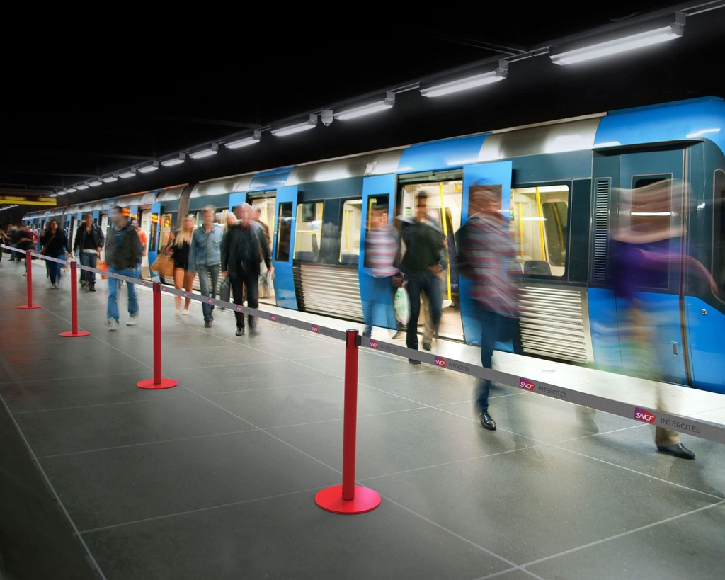 Muestra del poste con cinta extendida realizando su función de separar espacios en una estació de tren